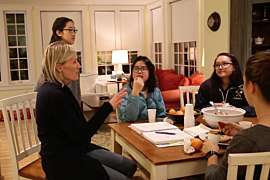 students gathered around a house counselor's dining room table